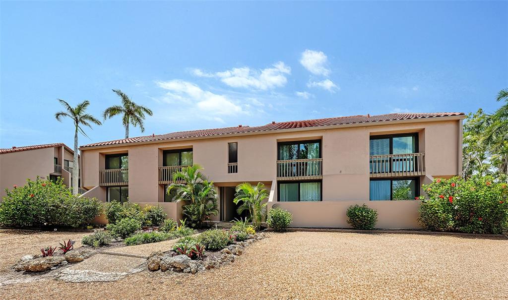 A two-story tan stucco building features balconies, large windows, and a gravel front yard — 218 PASS KEY ROAD UNIT 218, SARASOTA, FL