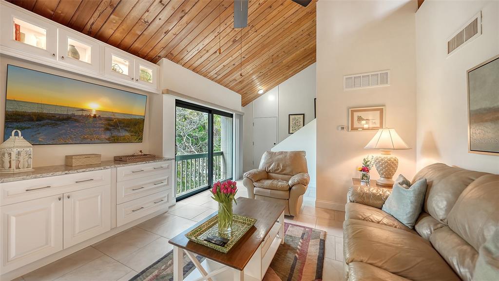 A living room features a vaulted wood ceiling, white cabinetry, a television, and a sofa — 218 PASS KEY ROAD UNIT 218, SARASOTA, FL