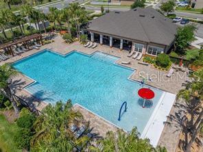 An aerial view shows a community swimming pool with a red umbrella and lounge chairs — 3457 MYSTIC POND LOOP, LAKELAND, FL