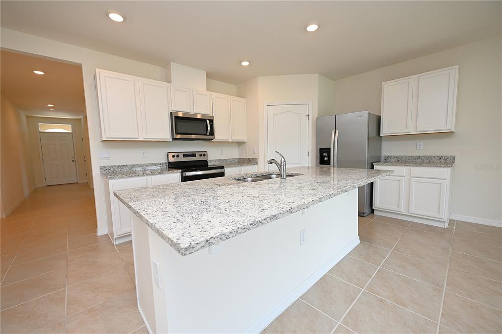 A kitchen features white cabinets, granite countertops, a center island, and stainless steel appliances — 3457 MYSTIC POND LOOP, LAKELAND, FL
