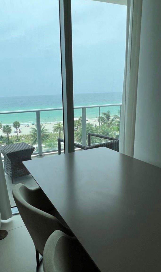 A dining table and chairs sit in front of a balcony overlooking the ocean — 4111 S Ocean Dr # 405, Hollywood FL 33019, HOLLYWOOD, FL