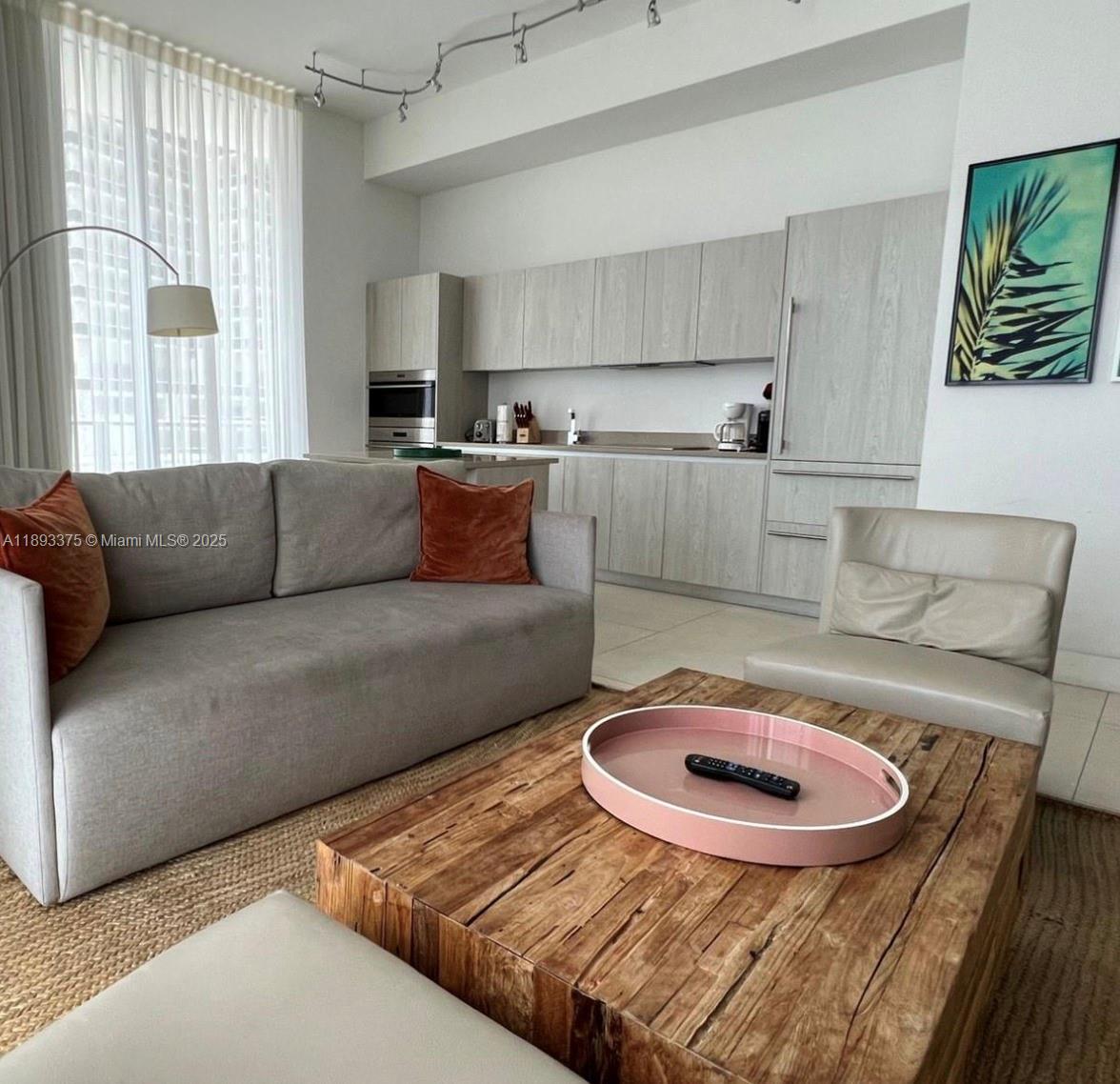 A living room with a grey sofa, wooden coffee table, and an open-concept kitchen — 4111 S Ocean Dr # 405, Hollywood FL 33019, HOLLYWOOD, FL