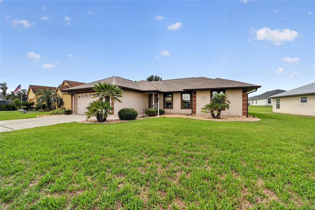 A single-story beige house with a brown shingled roof and a concrete driveway — 12220 SE 172ND LANE, SUMMERFIELD, FL