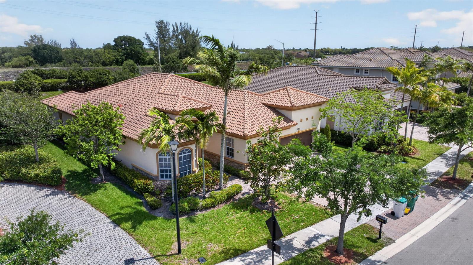 An aerial view of a single-story house with a tiled roof and palm trees — 8850 Miralago Way, Parkland FL 33076, PARKLAND, FL