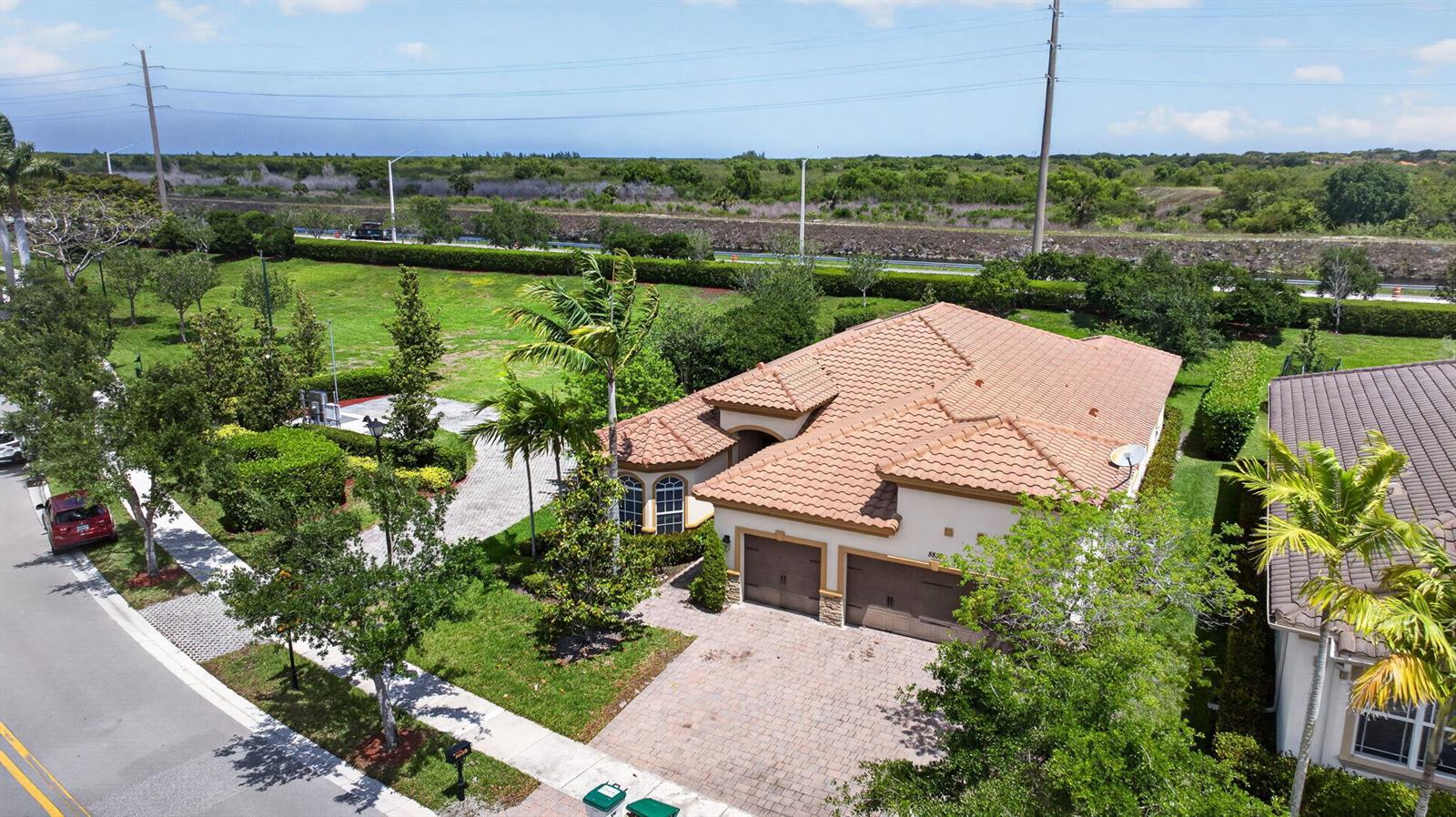 An aerial view shows a single-story house with a tiled roof and a paved driveway — 8850 Miralago Way, Parkland FL 33076, PARKLAND, FL