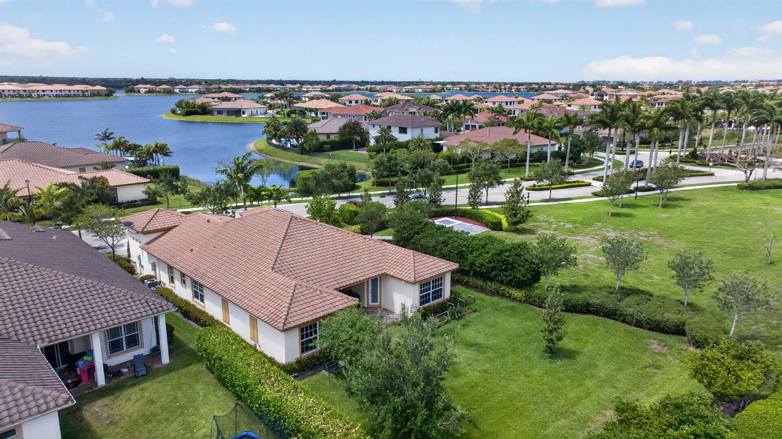 An aerial view shows a residential neighborhood with houses, a large lake, and green lawns — 8850 Miralago Way, Parkland FL 33076, PARKLAND, FL