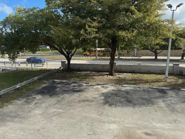 An outdoor parking lot with marked spaces sits in front of trees and a road — 10353 N Kendall Dr # 6, Miami FL 33176, MIAMI, FL
