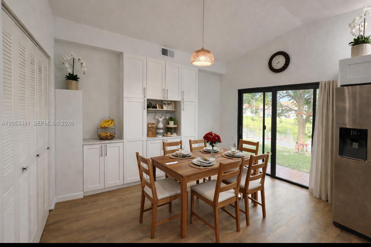 A dining room features white cabinetry, a wooden table with four chairs, and sliding glass doors — 9821 W Elm Ln # 9821, Miramar FL 33025, MIRAMAR, FL