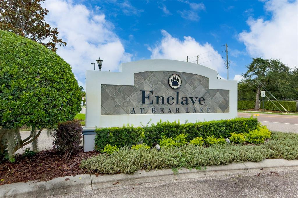 A stone-faced monument sign for Enclave at Bear Lake stands beside a road and landscaping — 5924 PAXTON COURT, APOPKA, FL
