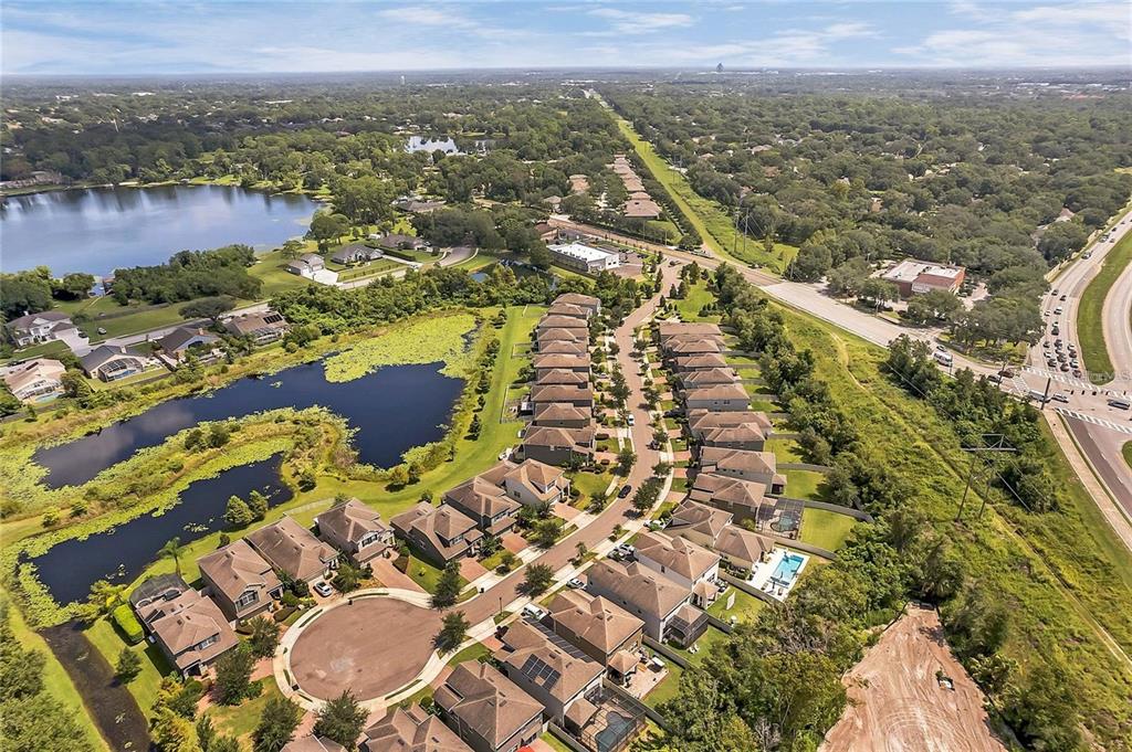 An aerial view of a suburban neighborhood featuring houses, a pond, and a nearby highway — 5924 PAXTON COURT, APOPKA, FL
