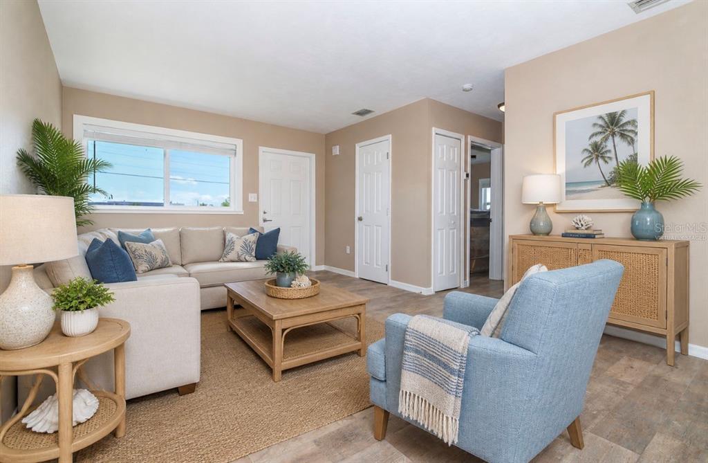 A living room with a beige sofa, blue armchair, wood coffee table, and tile flooring — 138 BUCKEYE AVENUE NW, PORT CHARLOTTE, FL