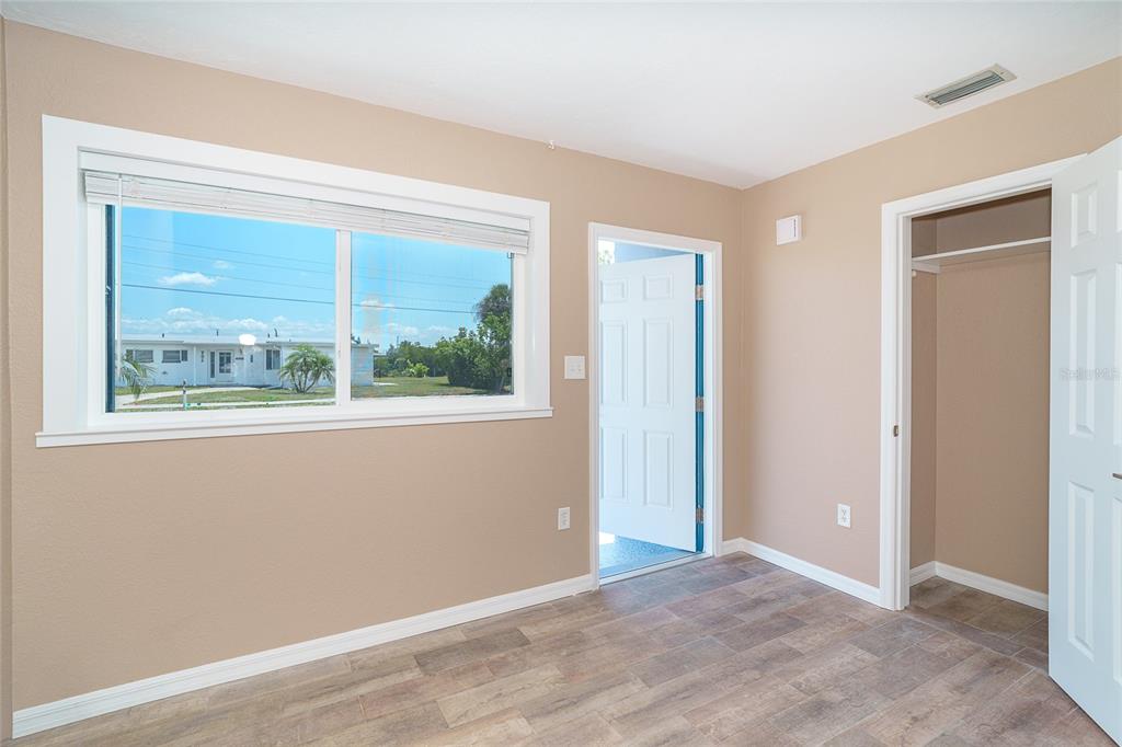 A room with light brown walls, wood-look flooring, a large window, and an open closet — 138 BUCKEYE AVENUE NW, PORT CHARLOTTE, FL