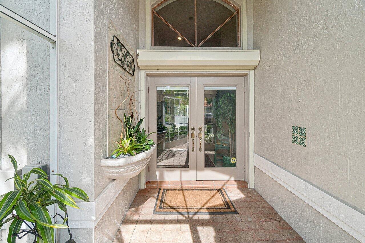 A covered entryway features double glass doors, a wall-mounted planter, and a tiled floor — 7398 Falls Road W, Boynton Beach FL 33437, BOYNTON BEACH, FL