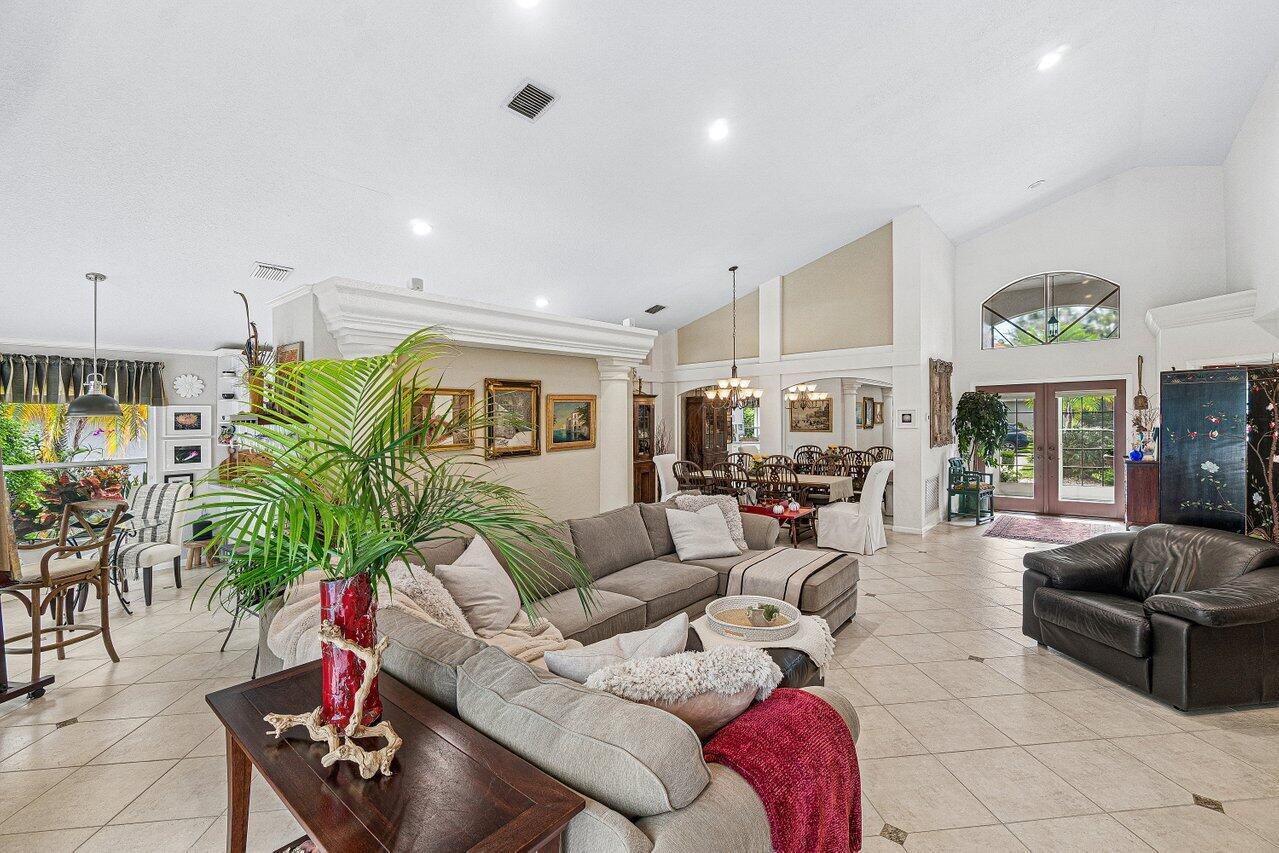 A spacious living room features vaulted ceilings, tile flooring, a sectional sofa, and dining area — 7398 Falls Road W, Boynton Beach FL 33437, BOYNTON BEACH, FL
