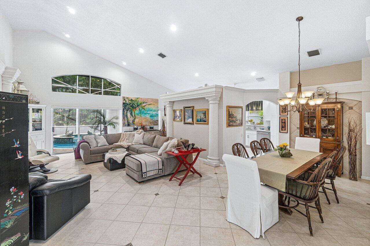 A bright, open-concept living and dining area features vaulted ceilings, tile floors, and a pool — 7398 Falls Road W, Boynton Beach FL 33437, BOYNTON BEACH, FL