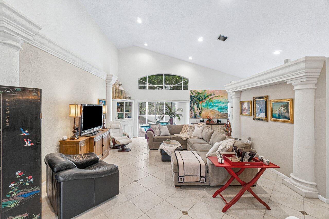 A living room features a vaulted ceiling, tile flooring, a sectional sofa, and a television — 7398 Falls Road W, Boynton Beach FL 33437, BOYNTON BEACH, FL
