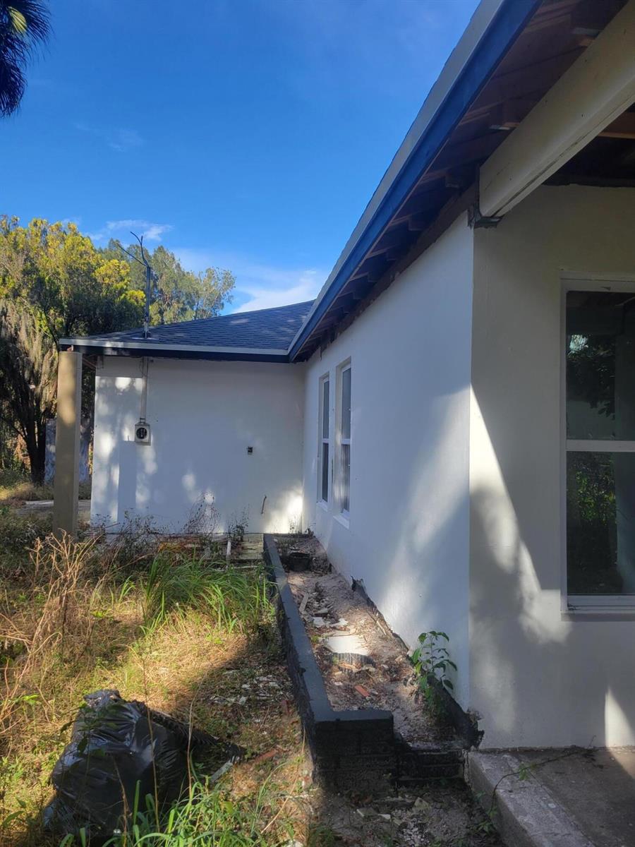 The exterior of a white stucco house features an exposed roofline and a brick planter — 1817 Palm Boulevard, Melbourne FL 32901, MELBOURNE, FL