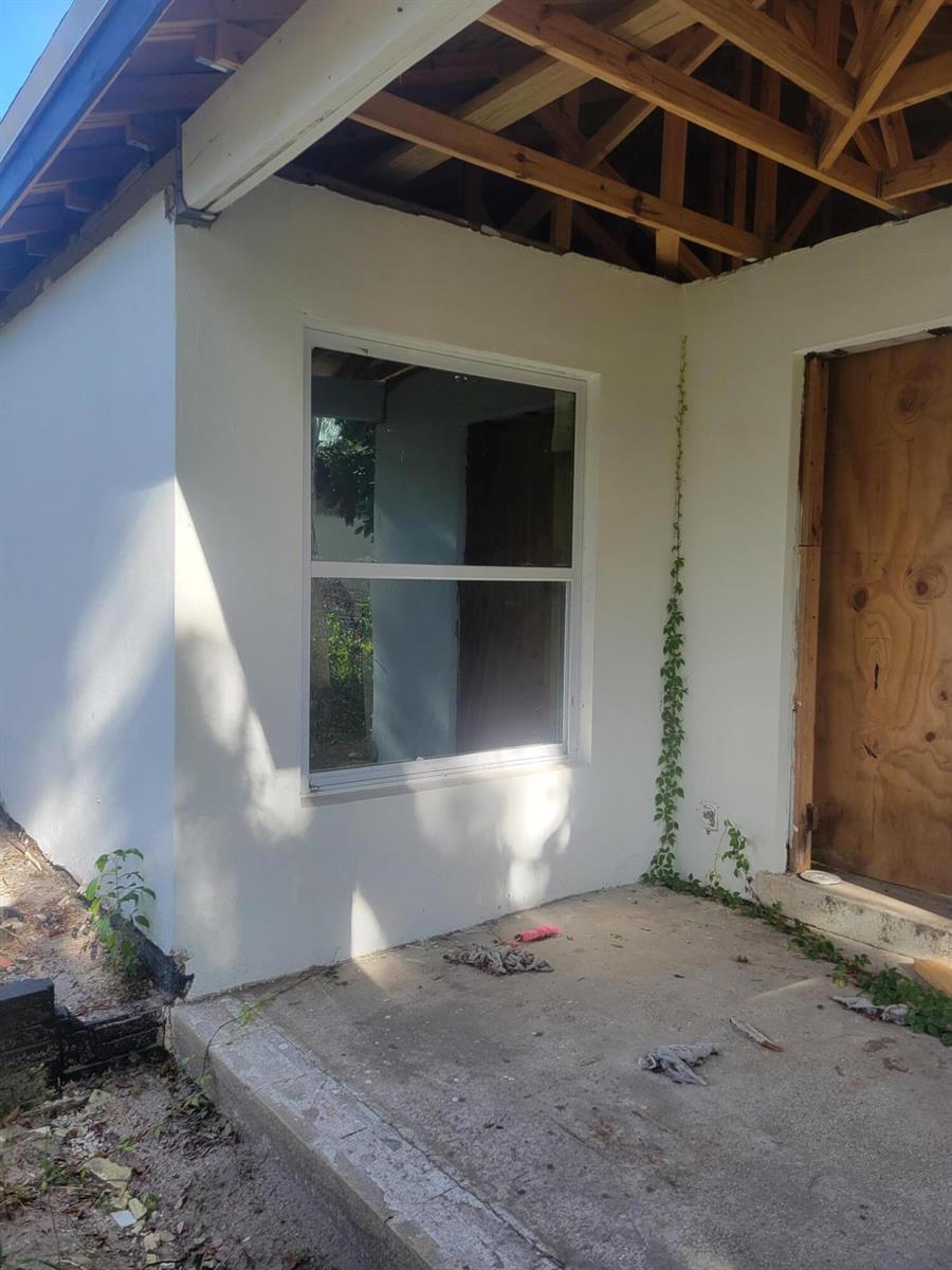 An exterior view of a house under construction with a window and a plywood door — 1817 Palm Boulevard, Melbourne FL 32901, MELBOURNE, FL
