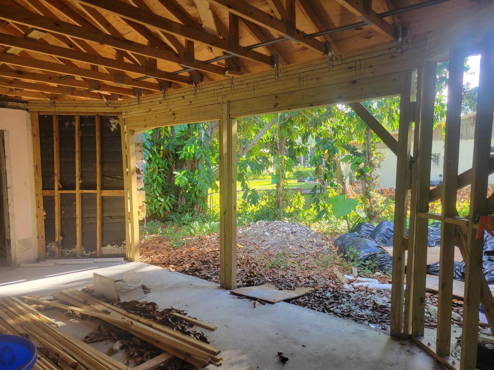 An unfinished room with exposed wooden framing and a large open wall facing a yard — 1817 Palm Boulevard, Melbourne FL 32901, MELBOURNE, FL