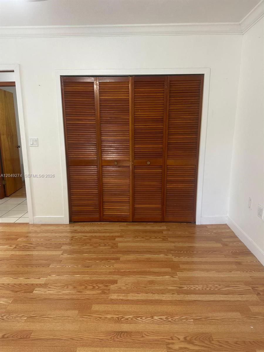 A room with wood flooring and a four-panel wooden louvered closet door — 19301 SW 220th St # 0, Miami FL 33170, MIAMI, FL