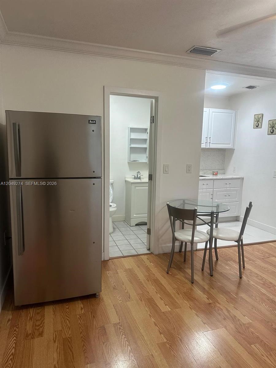 A stainless steel refrigerator stands next to a doorway leading to a small bathroom — 19301 SW 220th St # 0, Miami FL 33170, MIAMI, FL
