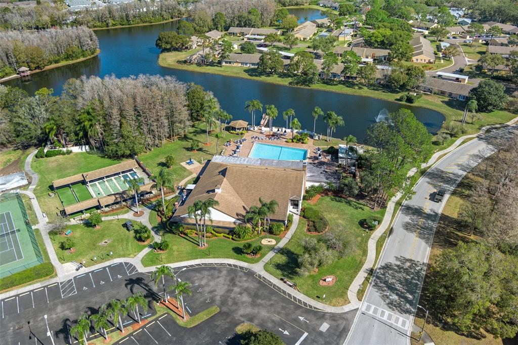 An aerial view shows a community clubhouse with a pool, tennis courts, and a lake — 4808 VESPER COURT UNIT 34, NEW PORT RICHEY, FL