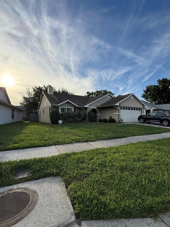 A single-story house with a tan exterior, a two-car garage, and a front lawn — 1215 TUXFORD DRIVE, BRANDON, FL