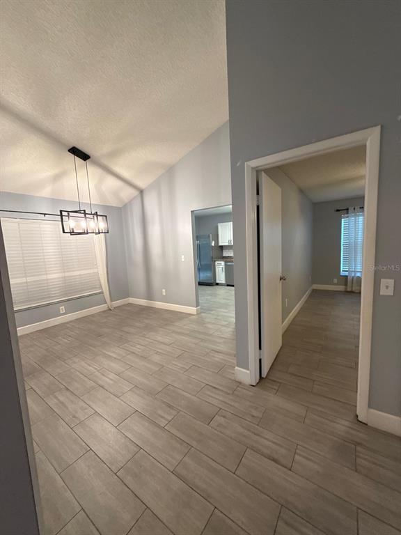 A dining area with a modern chandelier and light-colored tile floors leads to a kitchen — 1215 TUXFORD DRIVE, BRANDON, FL