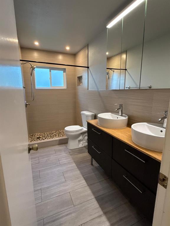 A modern bathroom features a double vanity with vessel sinks, a walk-in shower, and tile flooring — 1215 TUXFORD DRIVE, BRANDON, FL