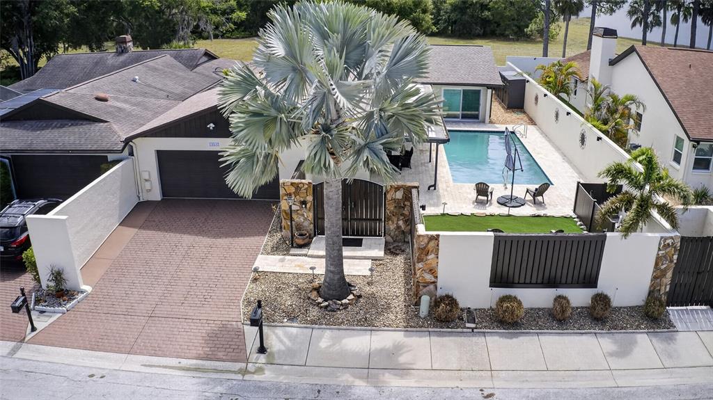 An aerial view shows a house with a paved driveway, a pool, and a palm tree — 13522 AVISTA DRIVE, TAMPA, FL