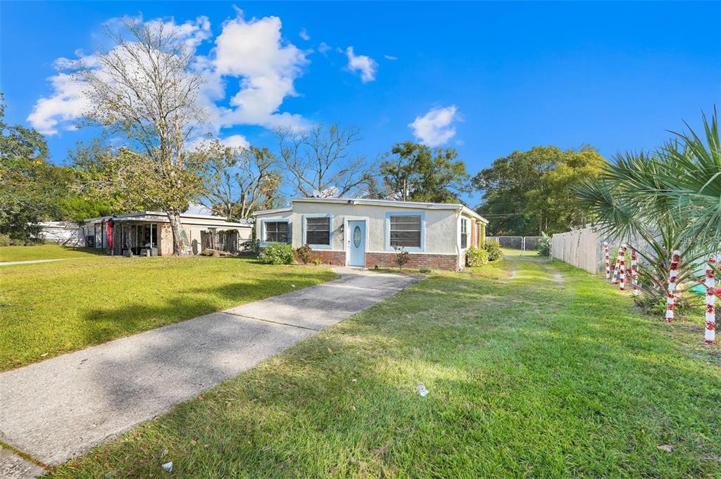 A single-story house with a concrete driveway, light-colored stucco walls, and a brick base — 107 GARRISON DRIVE, SANFORD, FL