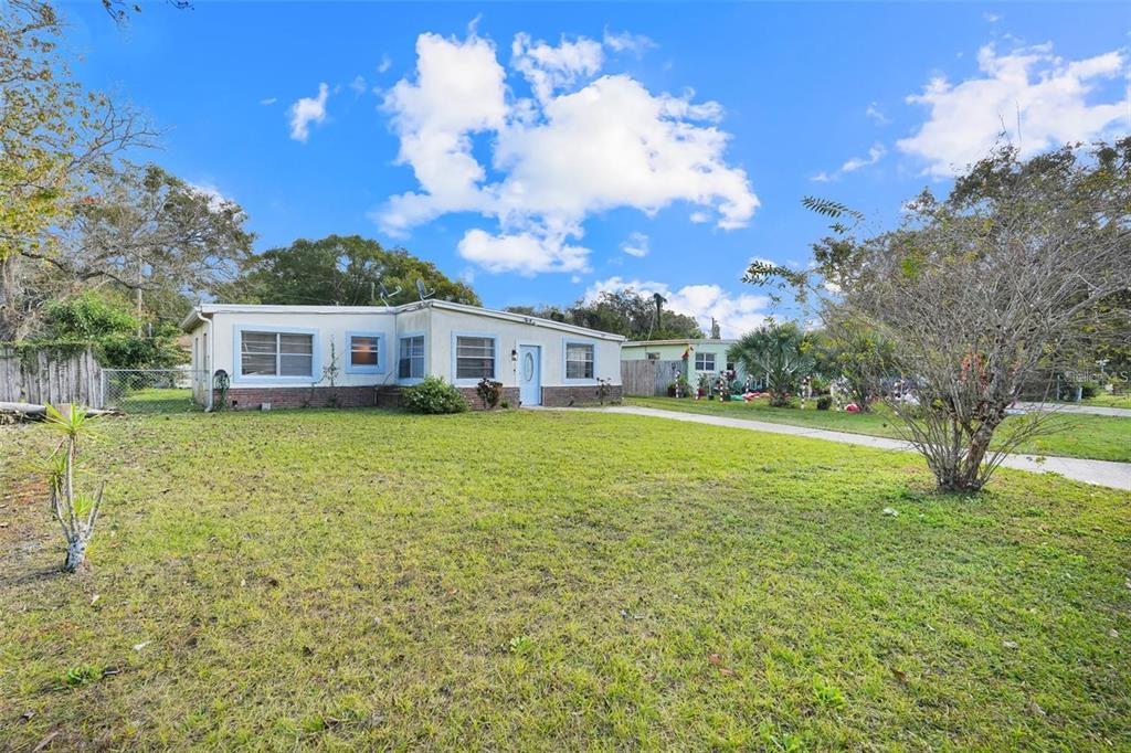 A single-story house with a light-colored exterior and a large front lawn under a blue sky — 107 GARRISON DRIVE, SANFORD, FL
