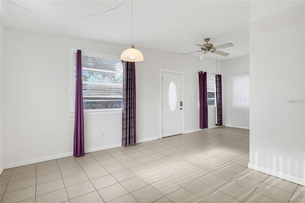 A bright room features light-colored tile flooring, white walls, purple curtains, and a ceiling fan — 107 GARRISON DRIVE, SANFORD, FL