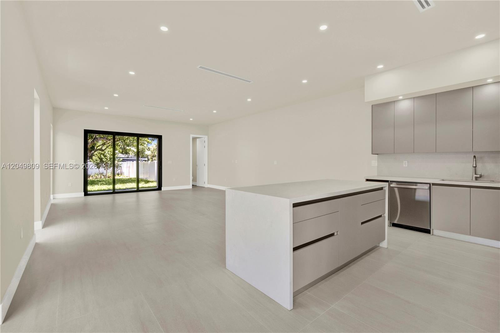 A modern kitchen with a white island and gray cabinets opens into a spacious living area — 2889 SW 35 Ave # 2887, Miami FL 33133, MIAMI, FL