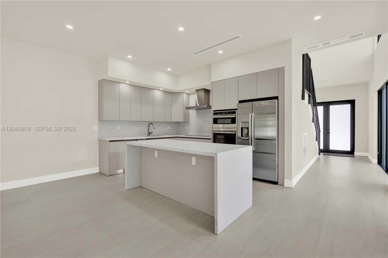 A modern kitchen features gray flat-panel cabinetry, stainless steel appliances, and a central island — 2889 SW 35 Ave # 2887, Miami FL 33133, MIAMI, FL