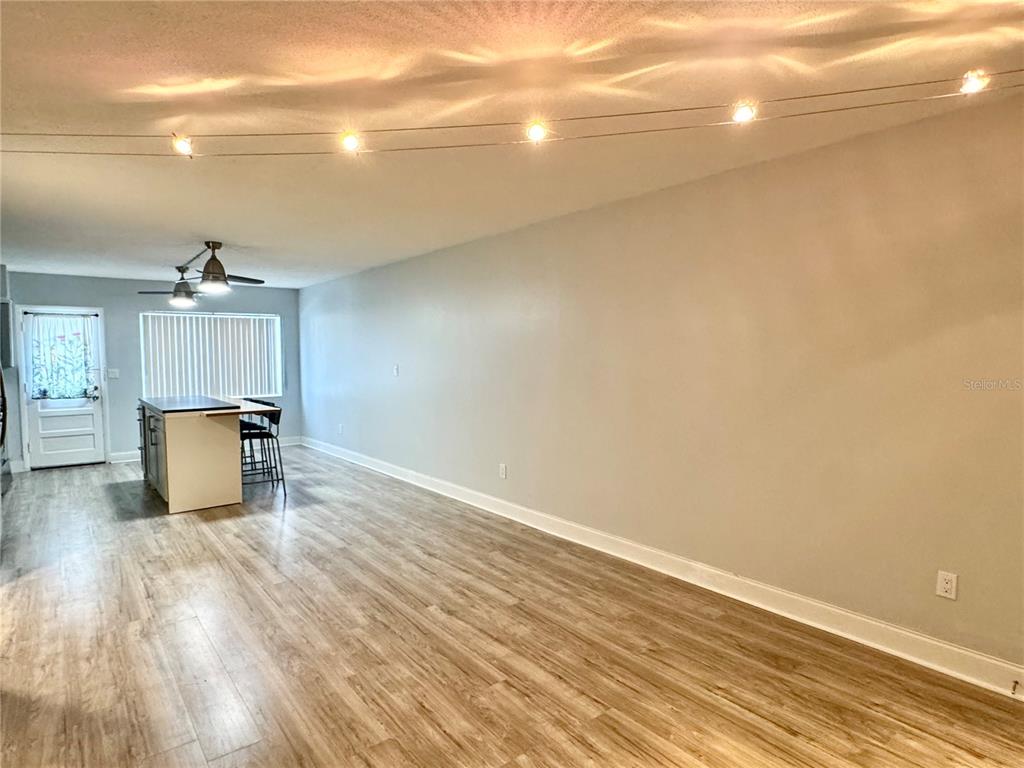 An open-concept room features light wood-look flooring, a kitchen island, and string lights — 825 N PRIMROSE DRIVE UNIT 110, ORLANDO, FL