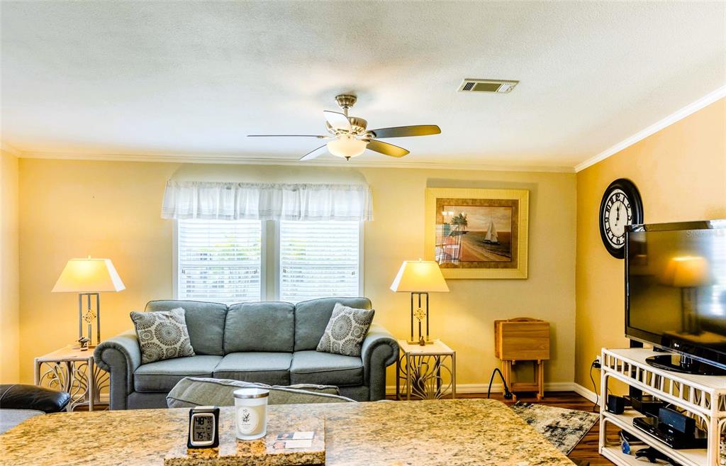 A living room features a gray sofa, two lamps, a ceiling fan, and a television — 2100 KINGS HIGHWAY UNIT 977, PORT CHARLOTTE, FL