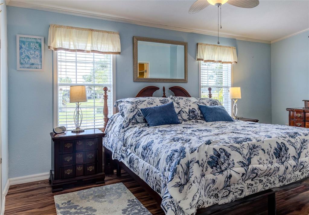 A bedroom features blue walls, a floral-patterned bedspread, two nightstands, and two windows with valances — 2100 KINGS HIGHWAY UNIT 977, PORT CHARLOTTE, FL