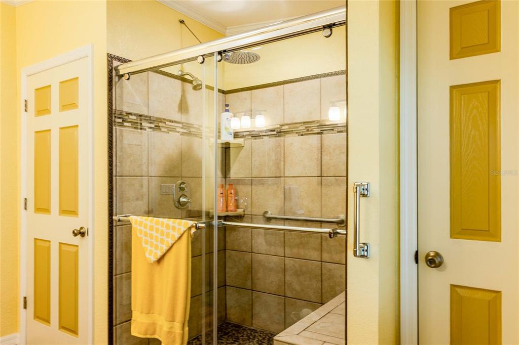 A bathroom features a tiled walk-in shower with a glass door and yellow walls — 2100 KINGS HIGHWAY UNIT 977, PORT CHARLOTTE, FL