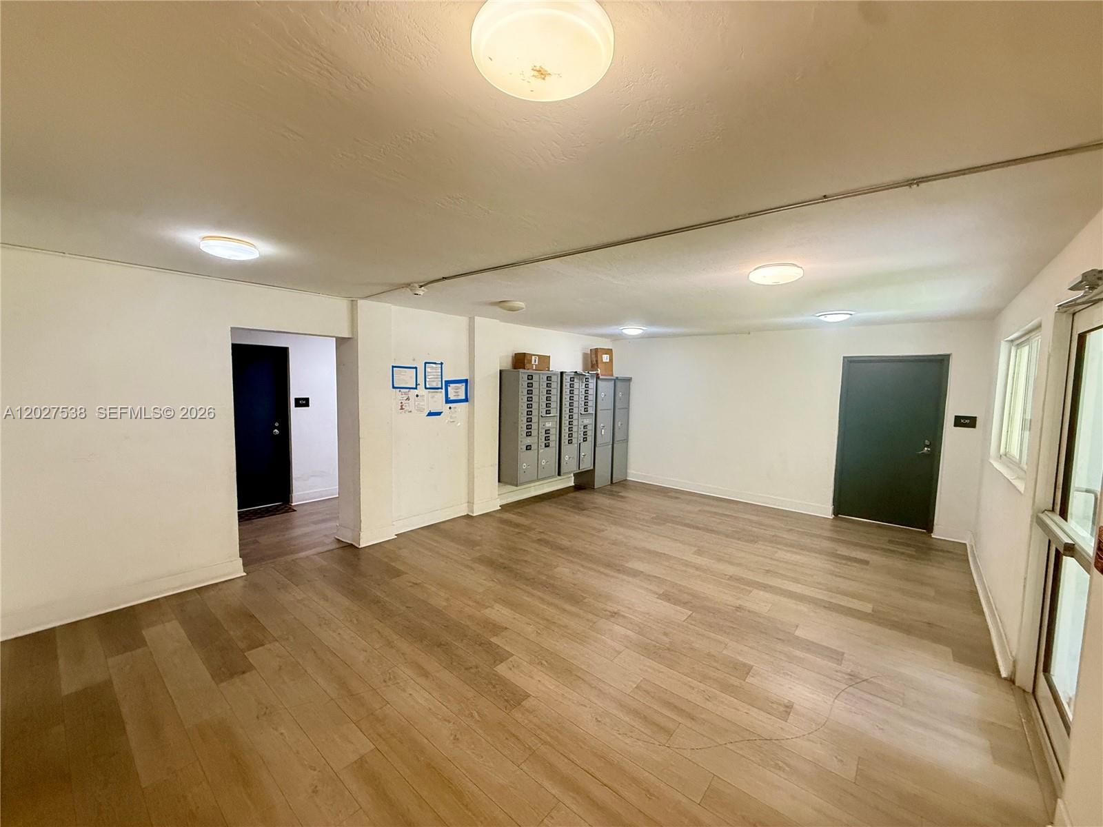 This room features light wood-look flooring, white walls, ceiling lights, and a bank of mailboxes — 143 SW 9th St # 206, Miami FL 33130, MIAMI, FL
