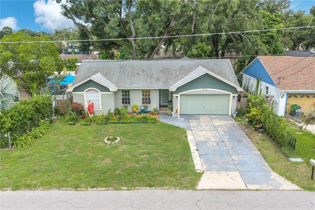 An exterior view of a single-story house with a green garage and a front lawn — 2114 W HANNA AVENUE, TAMPA, FL