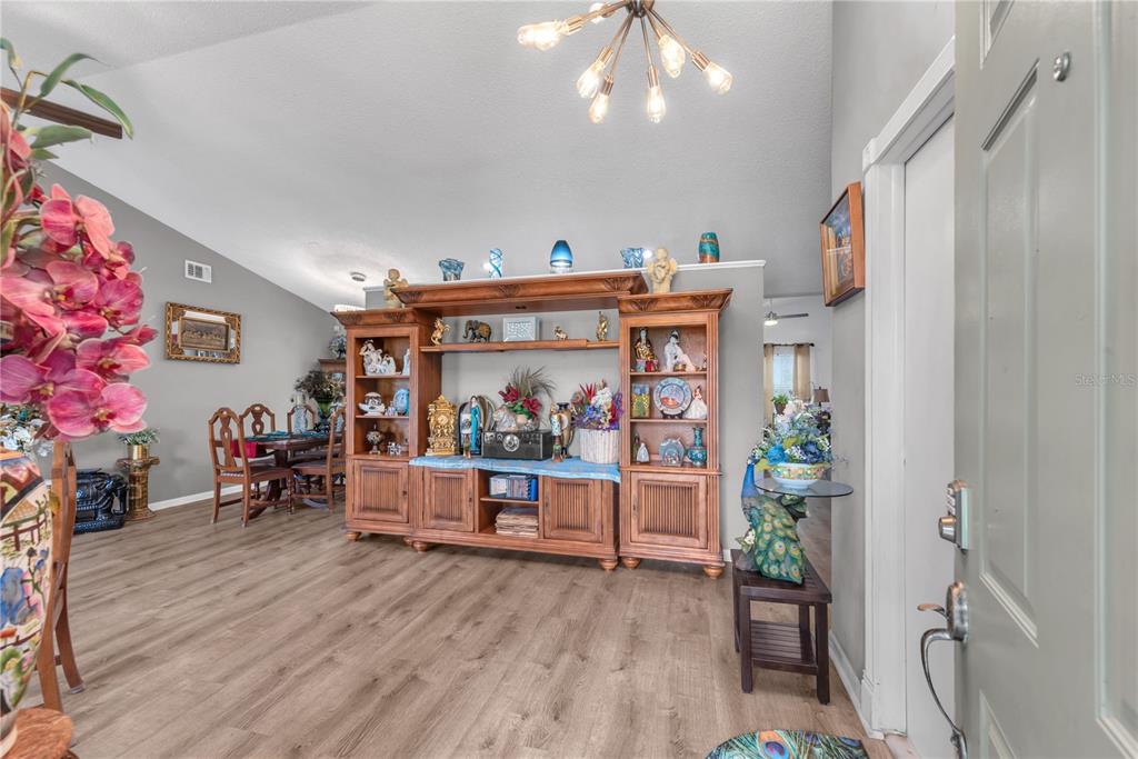 A living room features wood-look flooring, a large wooden entertainment center, and a modern chandelier — 2114 W HANNA AVENUE, TAMPA, FL