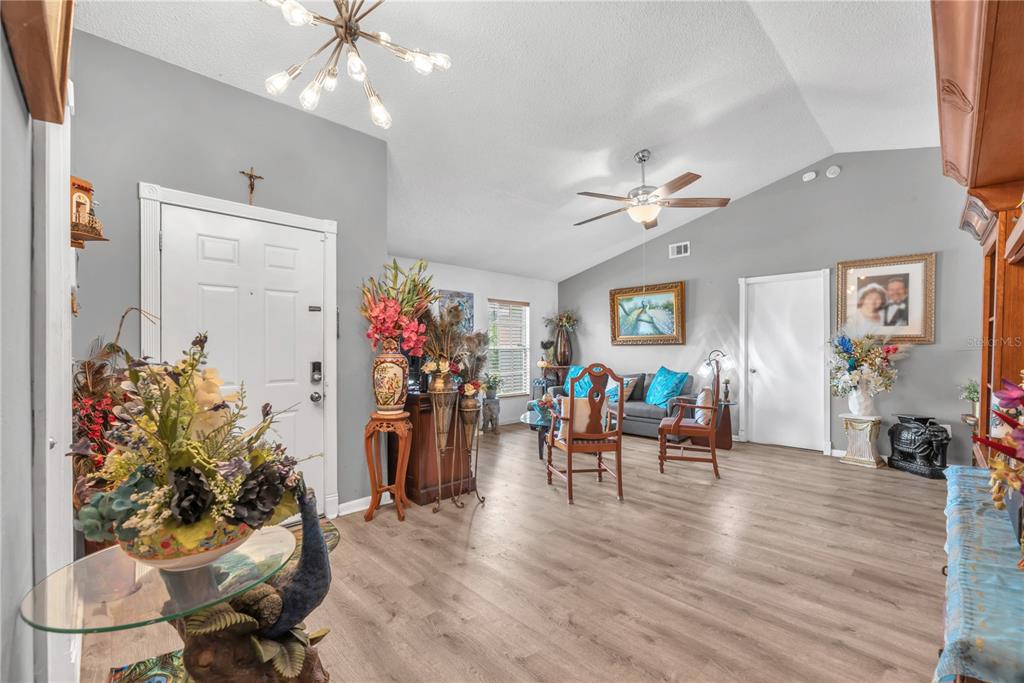 A living room with vaulted ceilings, light wood flooring, and a front entryway — 2114 W HANNA AVENUE, TAMPA, FL