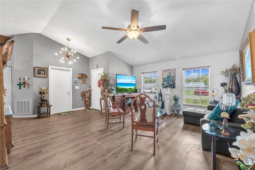 A living room with vaulted ceilings, wood-look flooring, a ceiling fan, and a television console — 2114 W HANNA AVENUE, TAMPA, FL