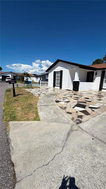 A white house with a stone-paved front yard and a concrete driveway under a blue sky — 6713 WILLOW SPRING COURT, TAMPA, FL