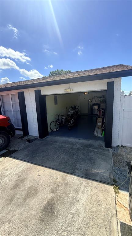 A view of a single-car garage with a concrete driveway and white brick exterior — 6713 WILLOW SPRING COURT, TAMPA, FL