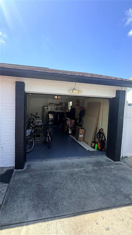 An open residential garage with a concrete floor, a bicycle, and various storage items inside — 6713 WILLOW SPRING COURT, TAMPA, FL