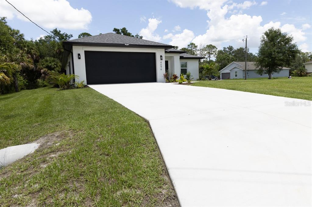 A modern single-story house with a black garage door and a concrete driveway — 4696 APRIL AVENUE, NORTH PORT, FL