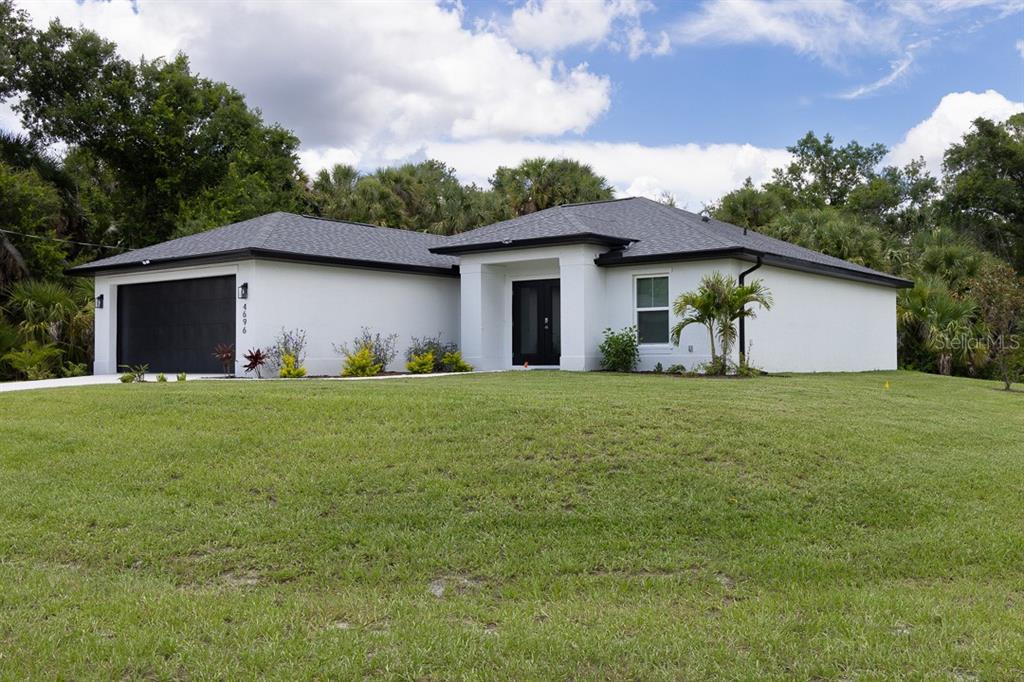 A single-story white house with a black garage door and a dark roof — 4696 APRIL AVENUE, NORTH PORT, FL