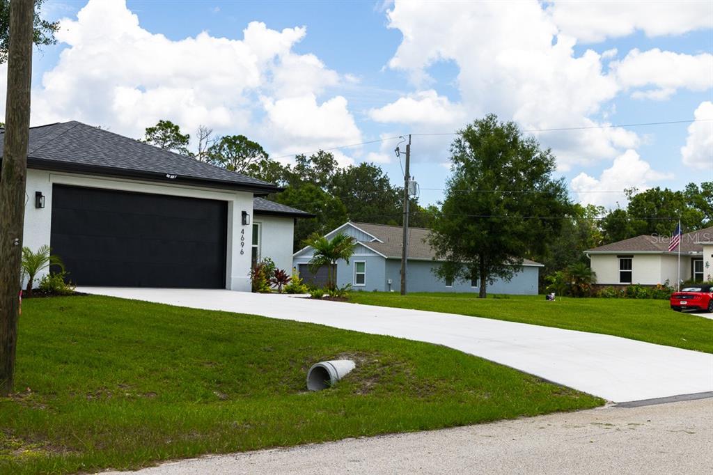 A modern single-story house with a black garage door and a concrete driveway — 4696 APRIL AVENUE, NORTH PORT, FL